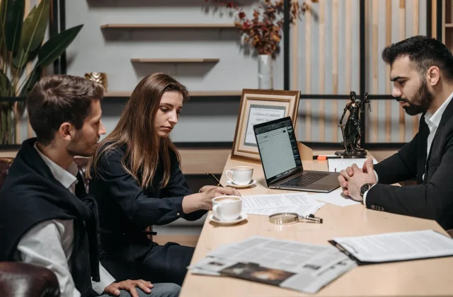 Clients and a supplier working through paperwork at an office table.
