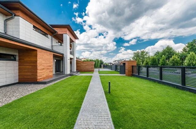The front garden of a contemporary house behind a low garden fence.